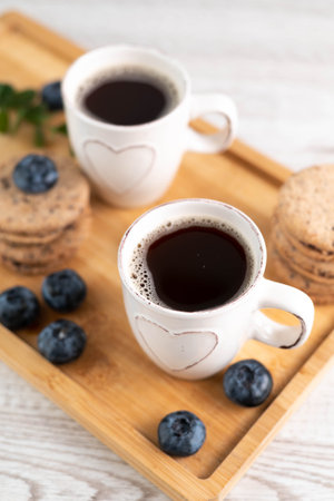 Blurred image on a tray of two cups of espresso, cookies and blueberries. Morning coffee concept.の写真素材