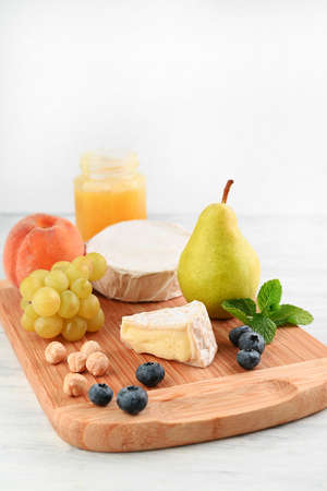 Blurred image of grapes, nuts, camembert, pear, peach, blueberry and honey on a light table.の写真素材