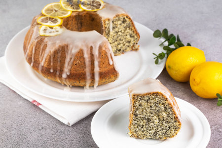 Lemon poppy seed Bundt Cake with icing and in a plate and a slice on a gray table.の写真素材
