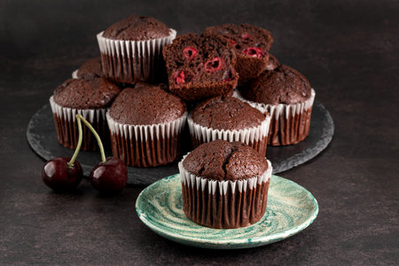 Chocolate muffins with cherries on a dark background.の写真素材