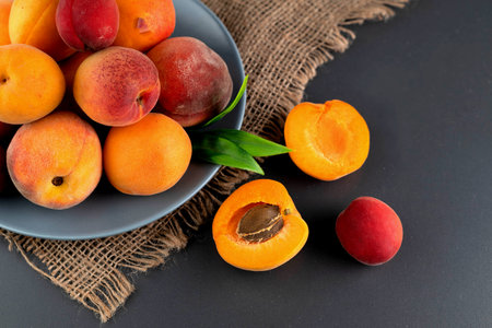 Ripe apricots in a plate on a dark table.Fruit background.の写真素材