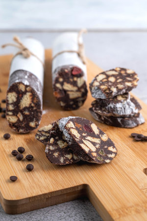 Chocolate salami on a wooden board and chocolate drops. Sweet food concept.の写真素材