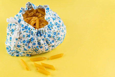 On a yellow background with space for text, a cotton bag with pasta. Sustainable lifestyle concept.Plastic free items.の写真素材