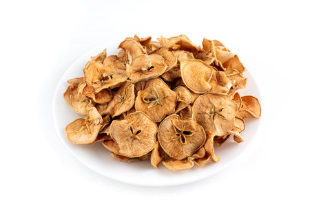 Dried apple slices in a white plate on a light background.の写真素材