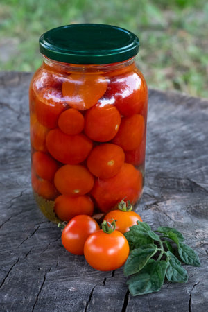 On a wooden background there are ripe tomatoes in the background of a can of canned tomatoes. The concept of preparing products for long-term storage.の写真素材