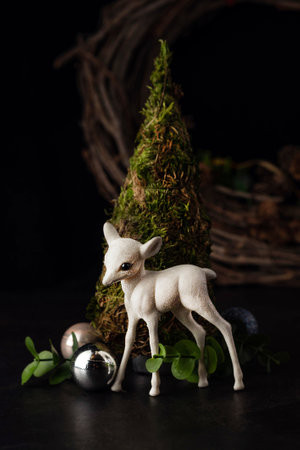 On a dark background, a blurry image of a small spruce and a white fawn, decor. New Year card.の写真素材