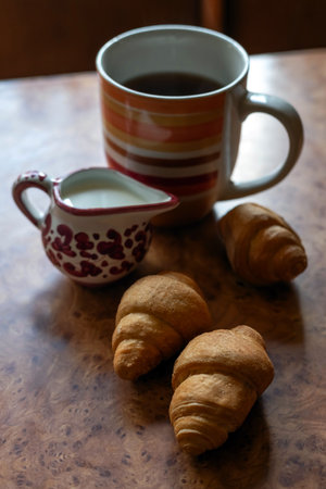 Blurred image of small croissants, a cup of coffee and milk. Homemade breakfast concept.の写真素材