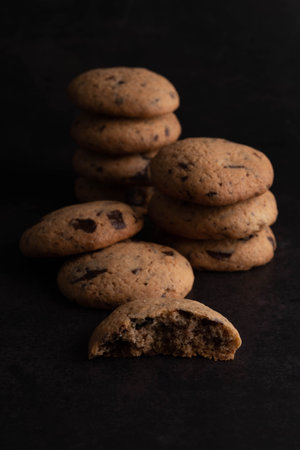 Cookies with chocolate pieces are laid out on a dark background.の写真素材