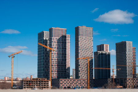 Construction of a modern high-rise building with cranes on a background of blue skyの写真素材