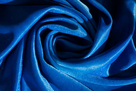 Close-up image of blue fabric, folds twisted in a circle. Closeup photo of folded wallpaper fabric with fabric design.の写真素材