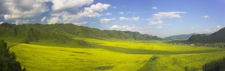 panorama with agricultural field, mountains and cloudy sky 
