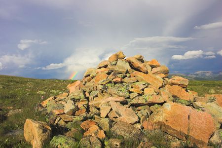 cairn and rianbow in cloudy skyの写真素材