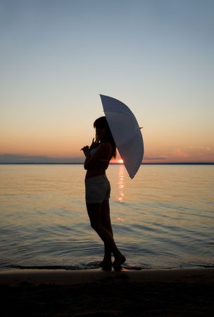 silhouette of young woman against summer sunsetの写真素材