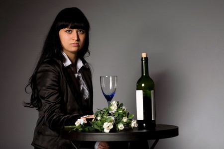 woman sitting at the table with flowers and wineの写真素材
