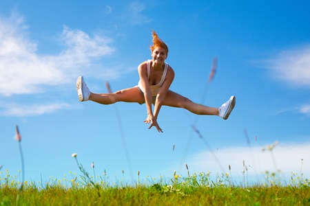 young happy girl jumping on sunny meadowの写真素材