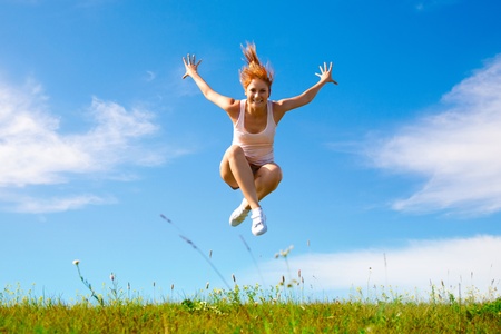young happy girl jumping on sunny meadowの写真素材