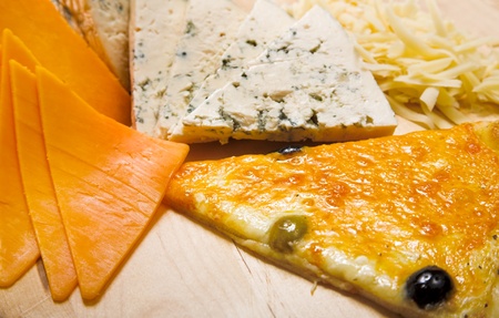 different sliced cheeses and pizza on wood plateの写真素材