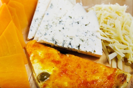 different sliced cheeses and pizza on wood plate