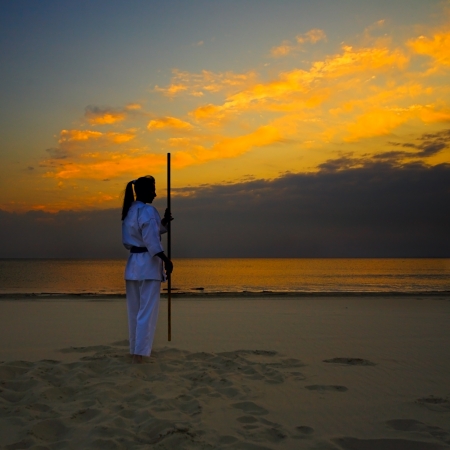 young woman training karate on sunset beachの写真素材