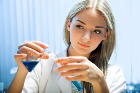 female researcher look at retort with blue liquidの写真素材