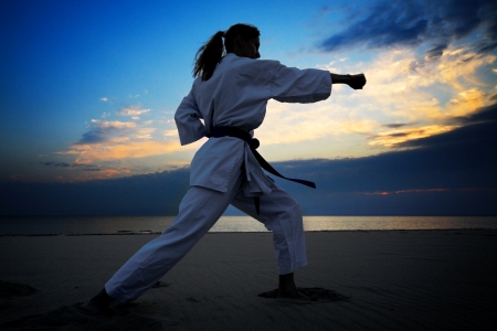 young woman training karate on sunset beachの写真素材