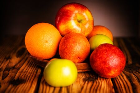 Apples and oranges on the wooden table