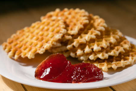 round belgian waffles on a white plate on a rustic wooden tableの写真素材