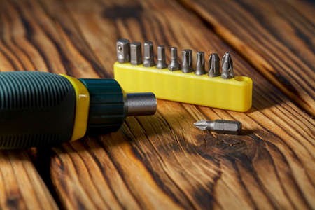 Set of heads (bits) and screwdriver on a wooden tableの写真素材