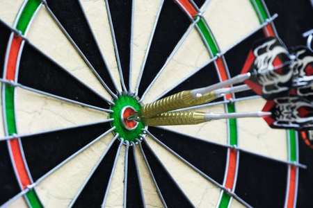 metal-tipped darts stuck in a competition dartboard