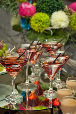glasses with red drink on a glass table on the background of flowersの写真素材