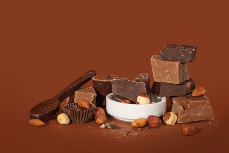 slices of chocolate on a brown background, a pile of chocolate with nuts,