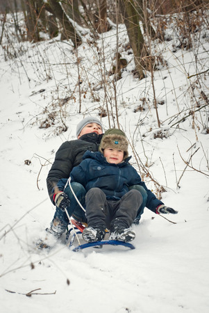 children are riding sledges in winter in the fresh air, on holidaysの写真素材