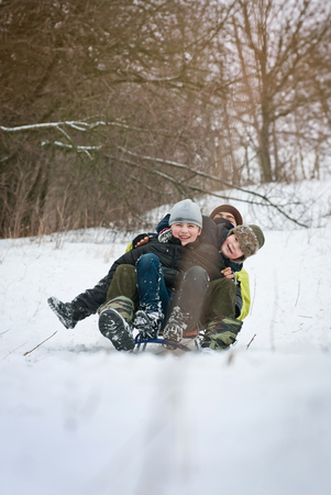 children are riding sledges in winter in the fresh air, on holidaysの写真素材