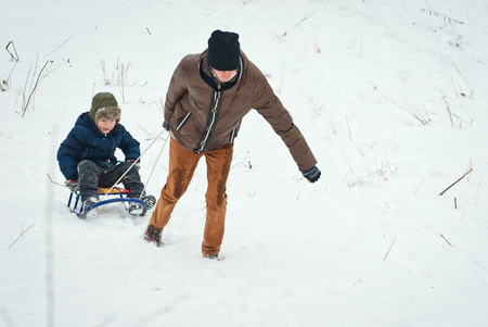 children are riding sledges in winter in the fresh air, on holidaysの写真素材