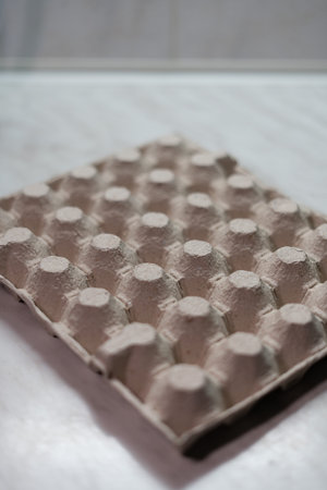 An empty cardboard egg carton on a table. Selective focus.