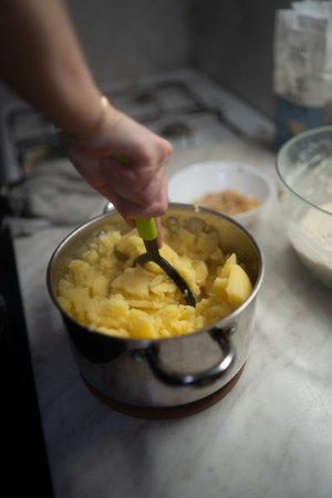 Mashed potatoes in a saucepan with a woman's hand.の写真素材