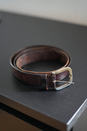Brown belt on a black wooden table. Selective focus with shallow depth of field.
