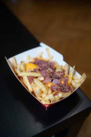 French fries with bacon and cheese in a box on a wooden table