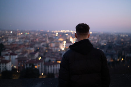 Young man looking over the city at nightの写真素材