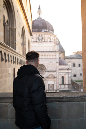 Young man in a black jacket looking at the city of Italy