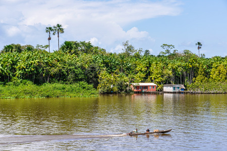 Local boat and a house as seen from the boat on the Amazon River in Brazil.