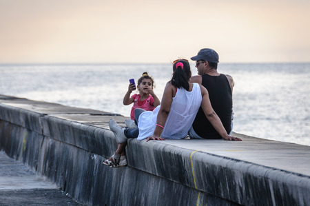 Family having a calm moment at sunset in the Malecon Avenue in Havana, the capital of Cubaのeditorial素材