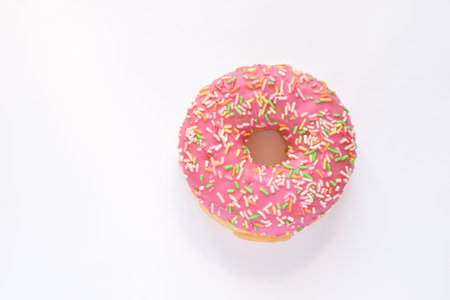 Pink donut with sprinkles isolated on white background, top viewの写真素材