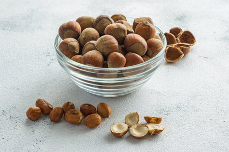 Hazelnuts in a glass bowl on a light concrete background.の写真素材