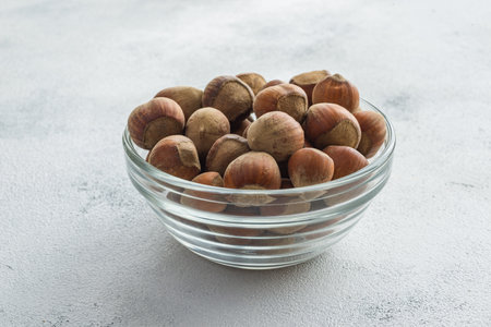Hazelnuts in a glass bowl on a light concrete background.の写真素材