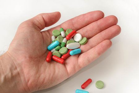 Hand is holding and showing some medicine pills on white backgroundの写真素材