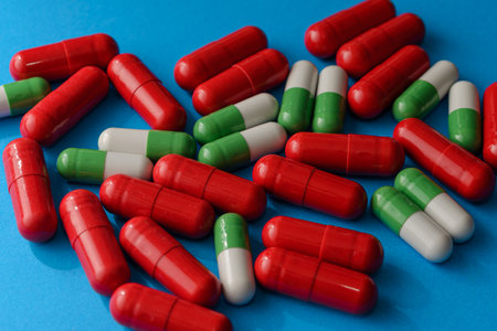 Red and green-white capsules on blue background, close-up of medicine pillsの写真素材