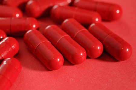 Close-up view of medicine red capsules or pills on red backgroundの写真素材