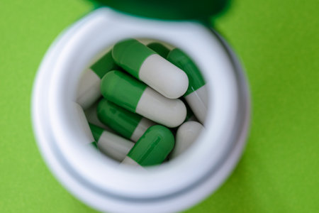 Green and white pills or capsules in white container close-up viewの写真素材