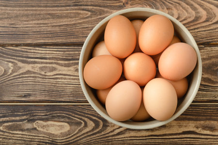 Raw eggs in a bowl on wooden background top view.の写真素材